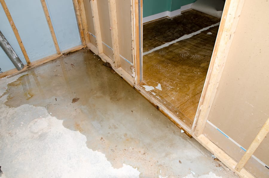 Water damage visible along a concrete slab floor caused by an undetected plumbing leak.