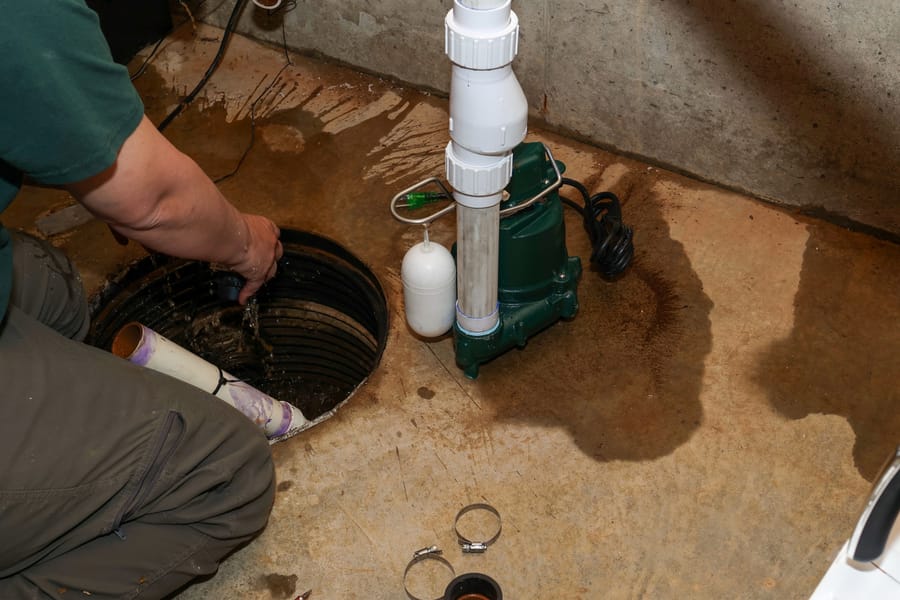 Technician servicing a basement sump pump system to prevent water damage.