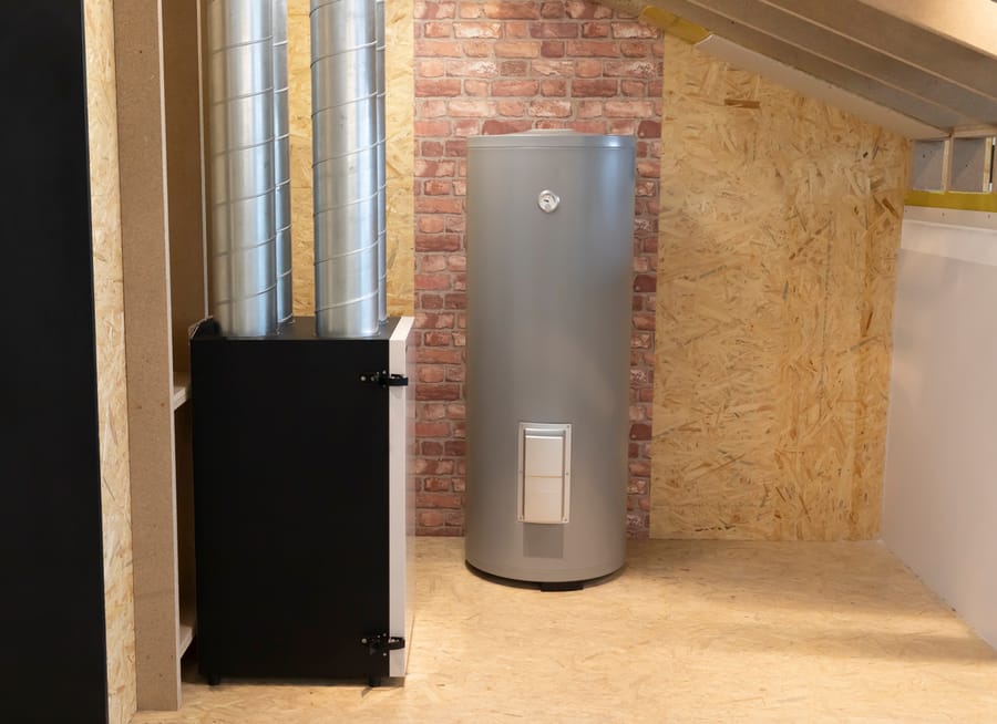 grey tanked water heater in basement in front of brick wall